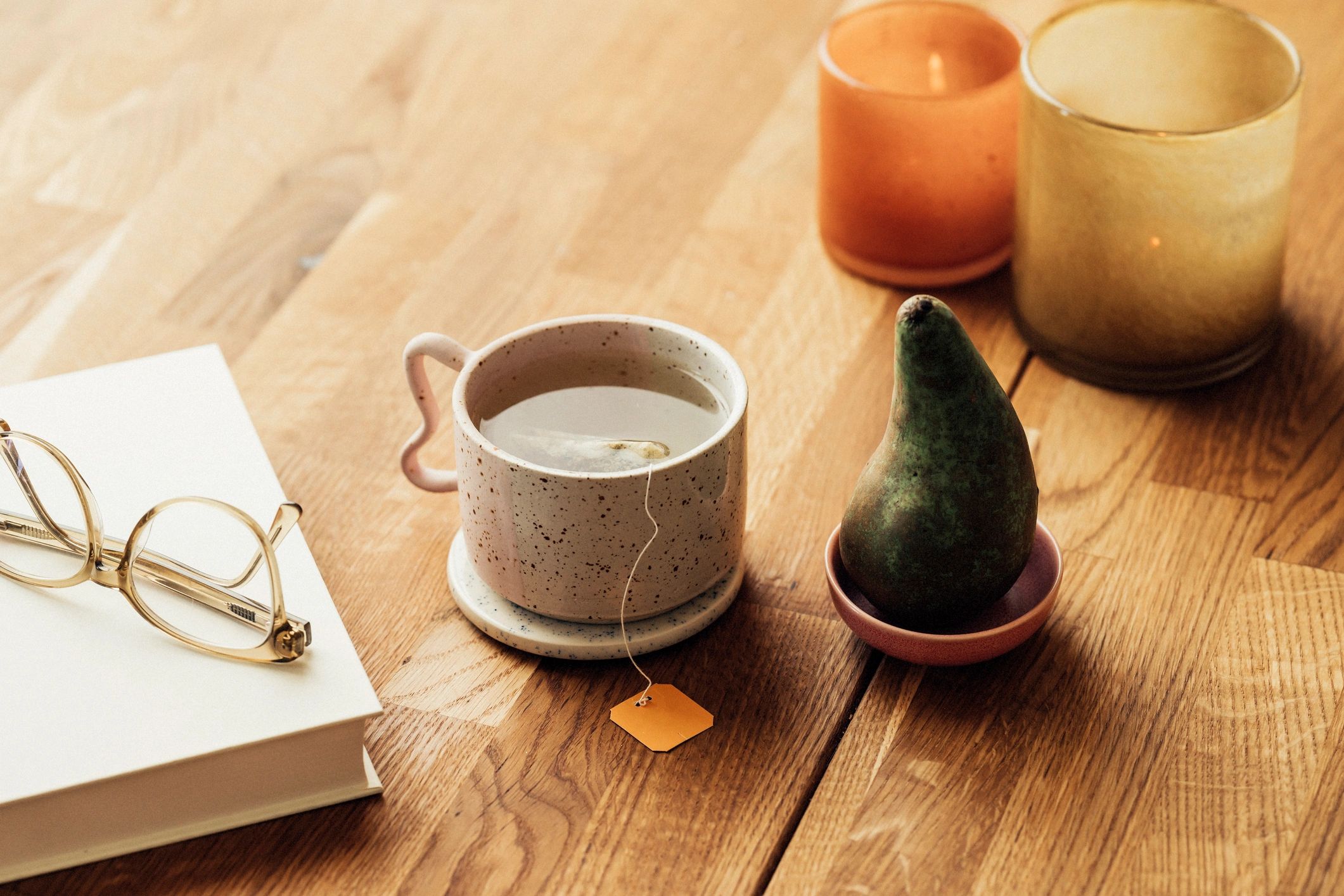 Herbal tea beside a book and candles for a calm wellness routine