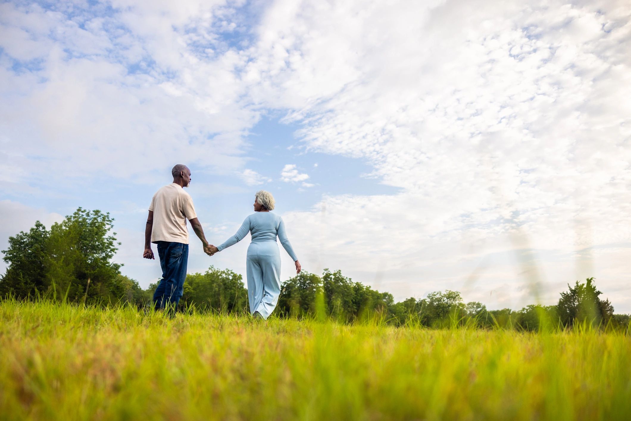 Senior couple walking together in a green pasture